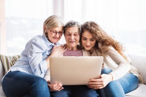 A teenage girl, mother and grandmother with laptop at home.