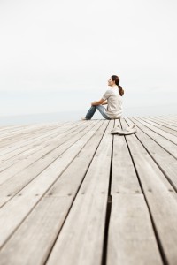 Woman day dreaming while sitting on a pier